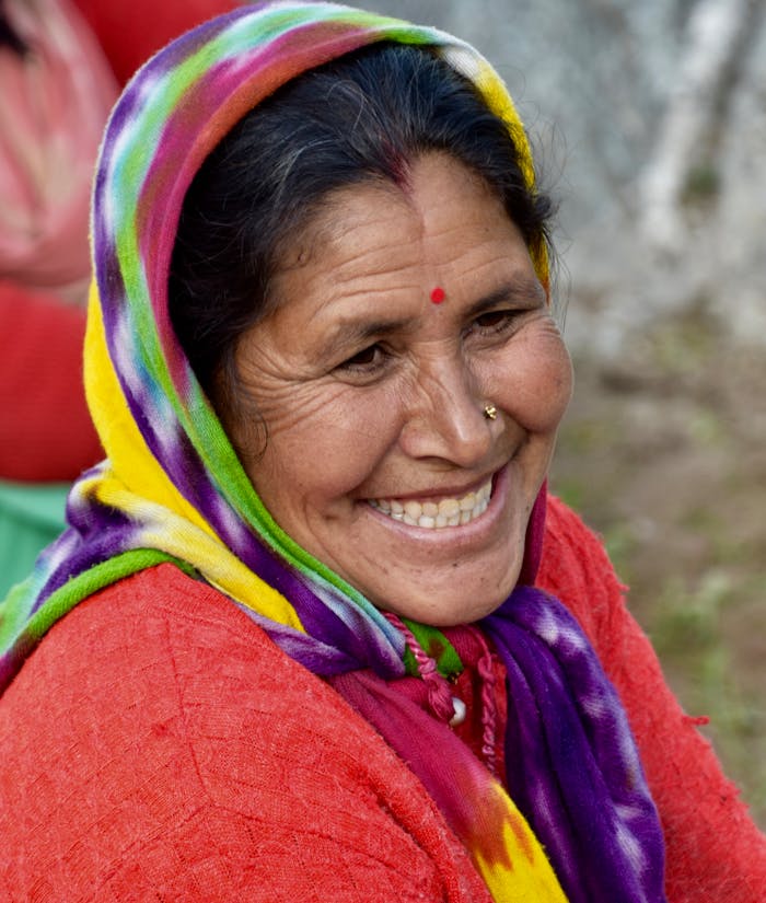 portfolio-img-04 Portrait of a joyful woman with bindi and nose piercing, showcasing vibrant textile patterns in Rudra Nath, India.